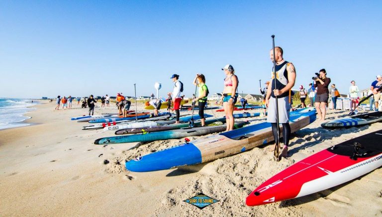 a group of people standing on top of a sandy beach
