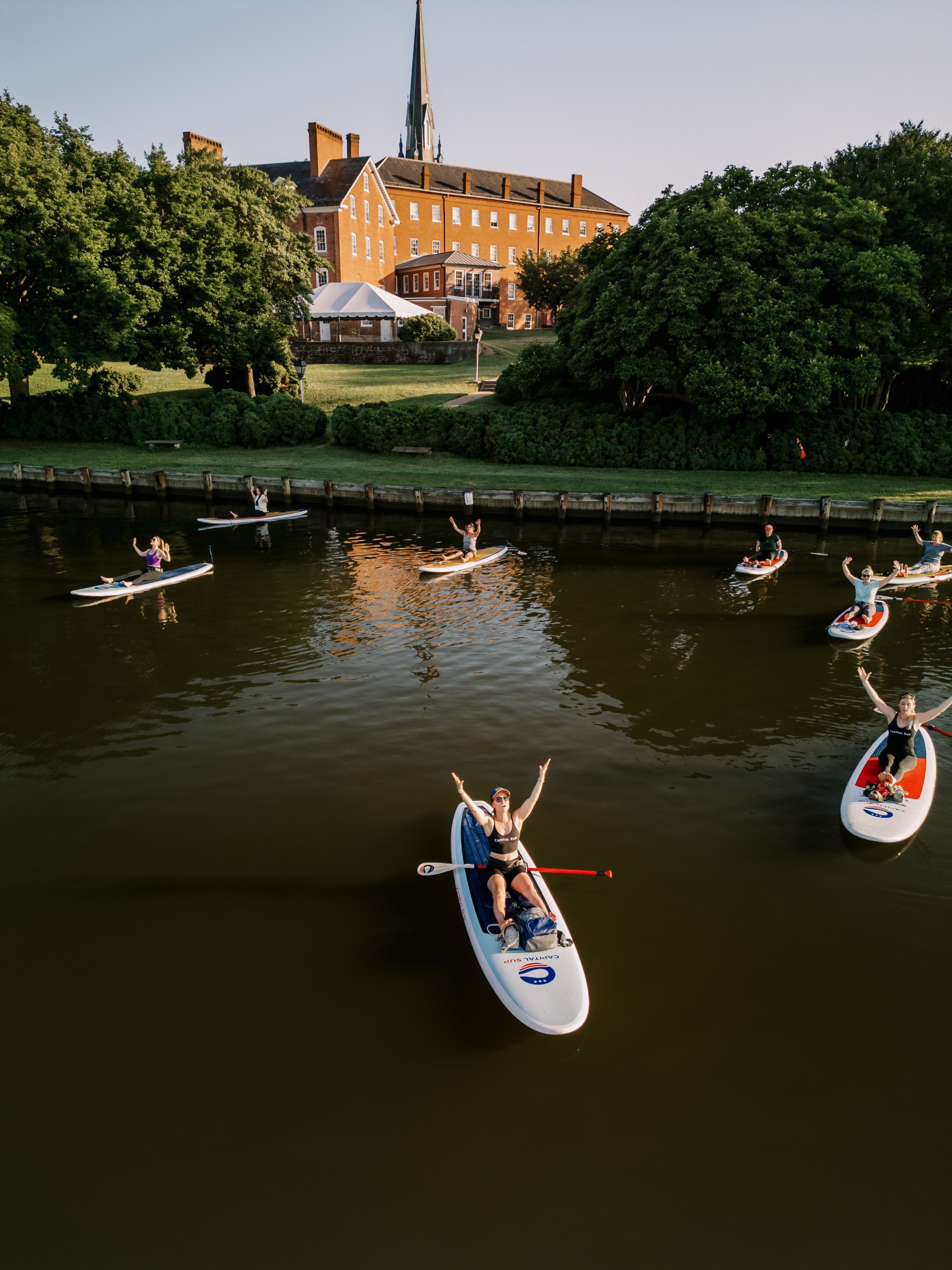 DJI_0088-060424_Sunrise Paddle and Yoga_Allie Cushley (1) a group of people riding on the back of a boat in the water