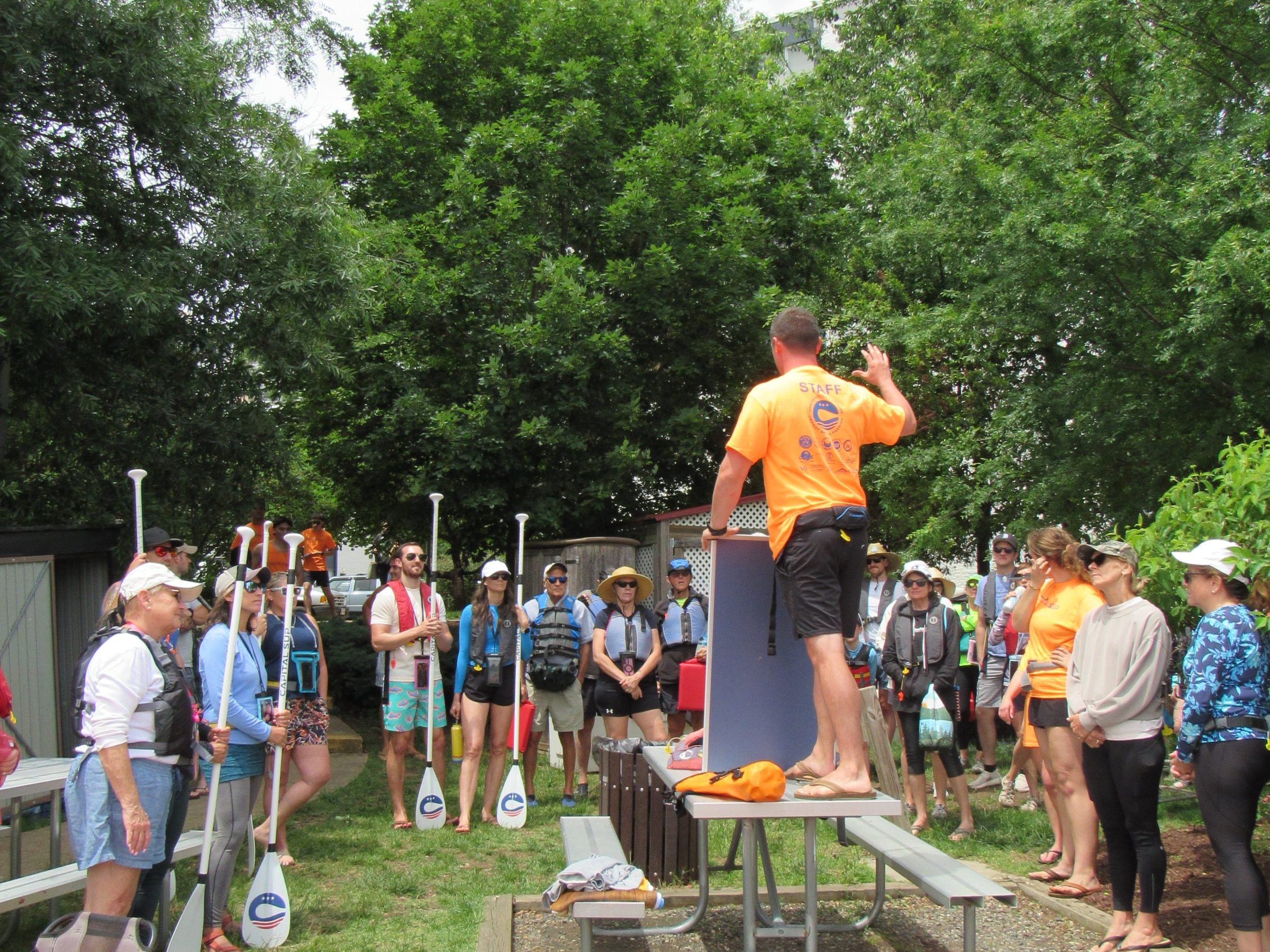 A group receiving kayak instruction outdoors with kayaks on grass.