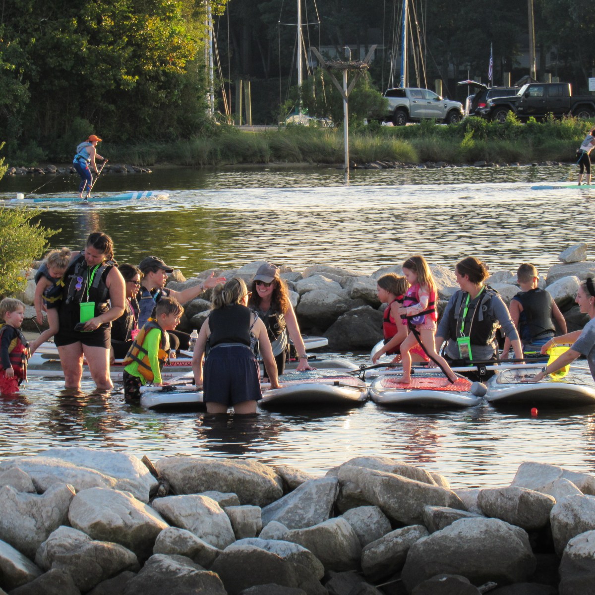 Group of people paddleboarding on a sunny day near a rocky shore.