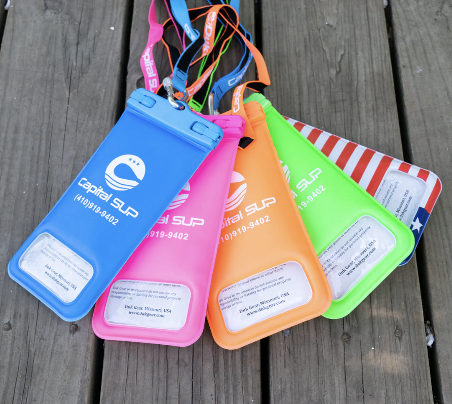 Four colorful waterproof pouches with lanyards on a wooden surface.