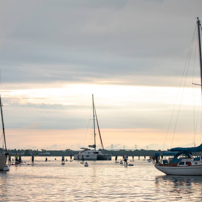 Sailboats anchored on calm water at sunrise or sunset.