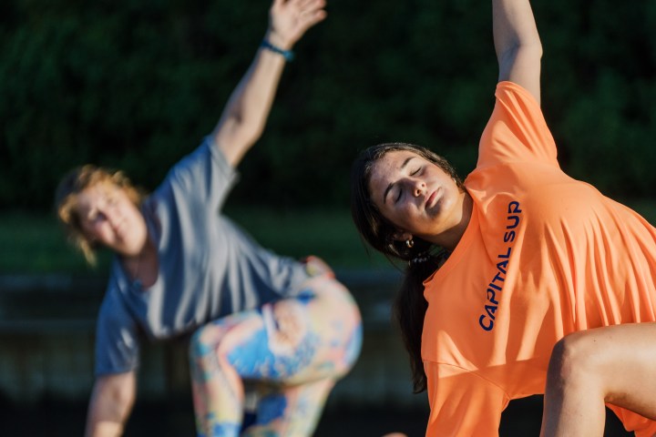 Two women doing yoga on paddleboards on a body of water.